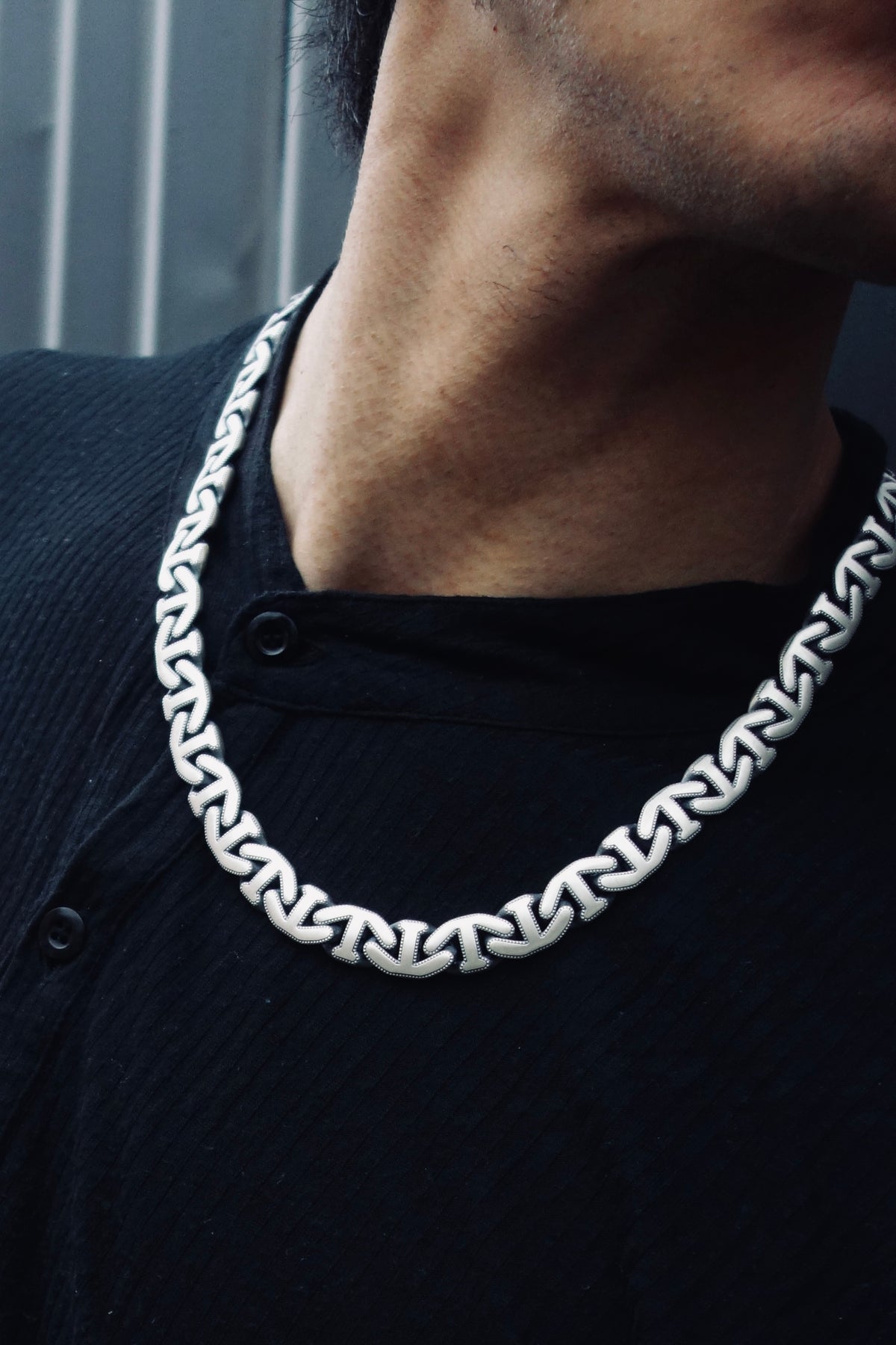 Nocturne Lock Chain worn at the neck, showing the width of the mariner links against a black collar